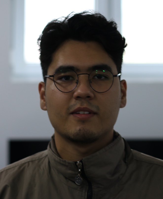 website design A man with dark hair and glasses, wearing a dark jacket, looking directly at the camera with a neutral