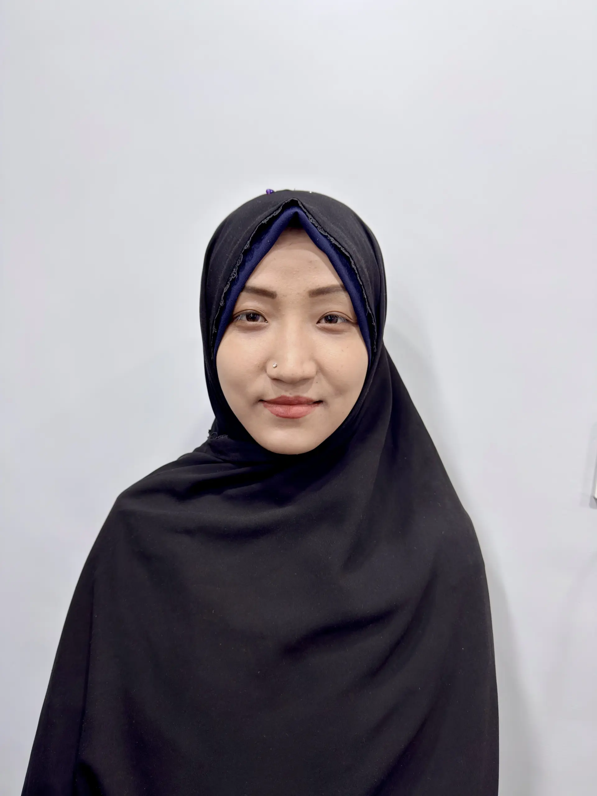 A woman wearing a hijab in front of a white background, representing a corporate website design