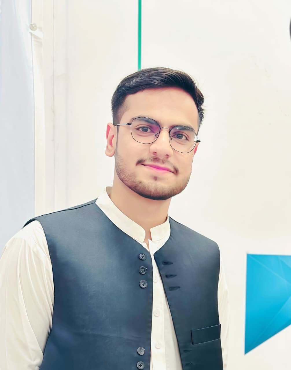 website design A man in a white shirt and a dark blue vest, with short dark hair and glasses, is smiling at the camera.