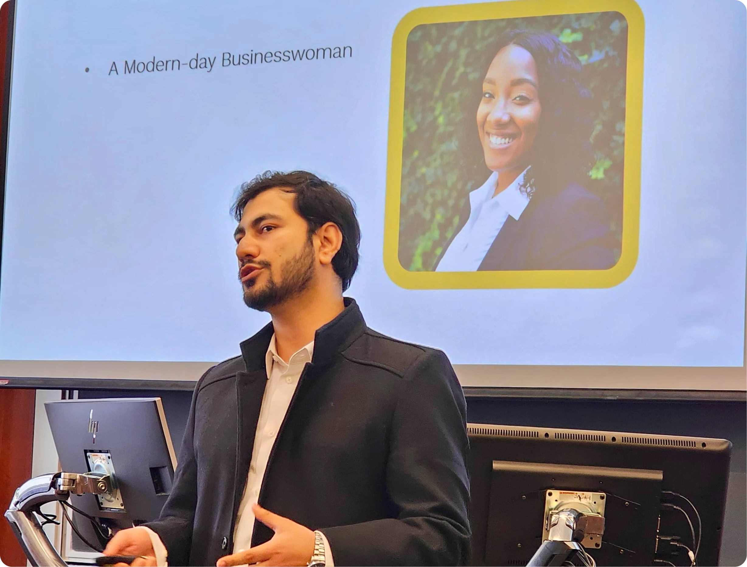 A man in a suit in front of a screen with a presentation slide about a businesswoman and a website design