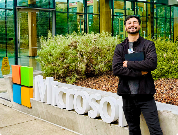 website design A man in a black jacket and pants stands in front of a building with a glass wall, holding a laptop and